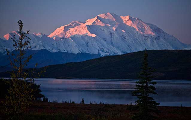 Mount McKinley, tinged pink with alpenglow, with Wonder Lake in the foreground NPS Photo / Jacob W. Frank