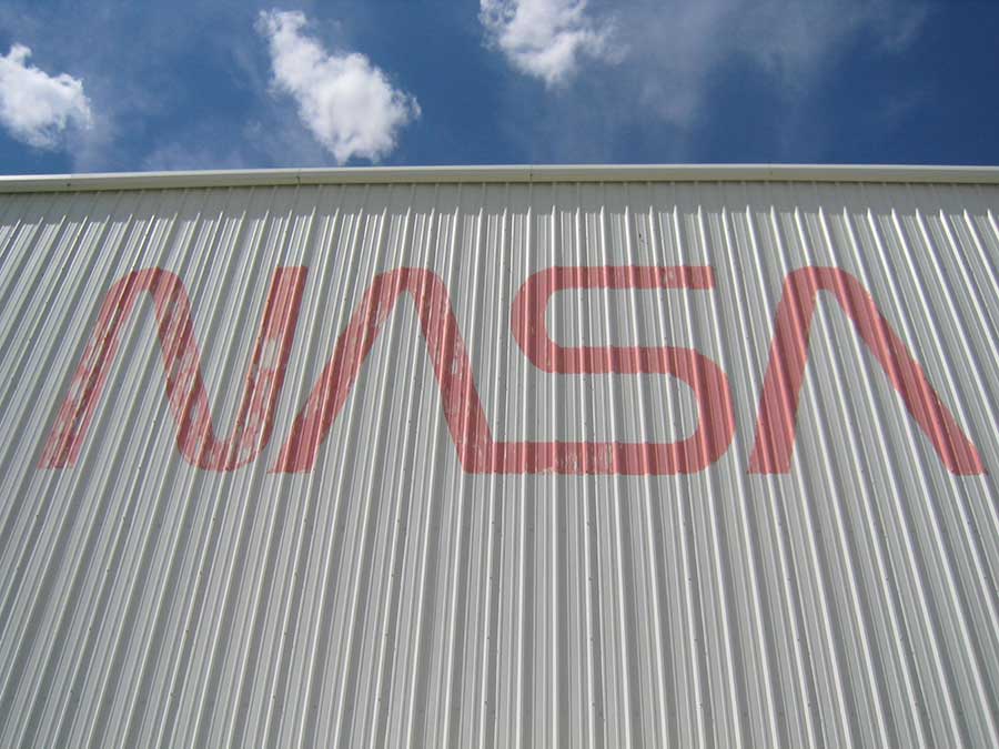 The NASA Logo (The "Worm") on the side of the High-Bay. The Worm was retired in 1992 in favour of the old NASA Insignia (The "Meatball"). This should give you a good idea of the last time the exterior of the high-bay was painted. Credits: Ketiltrout