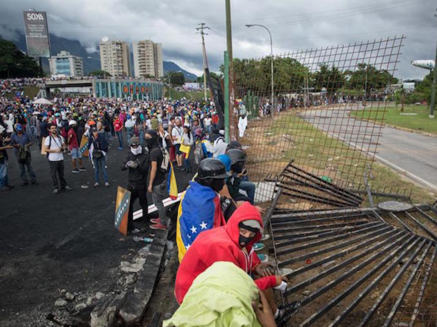 Protesters tear down security fence at the "Great General Francisco de Miranda" military base. Image Credit: EFE